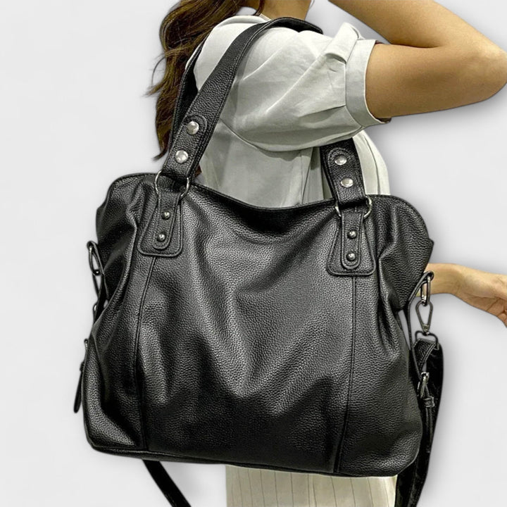 Vegan leather shoulder bag featuring an adjustable strap, multiple compartments, and a spacious design for versatile use as a large capacity tote. 1