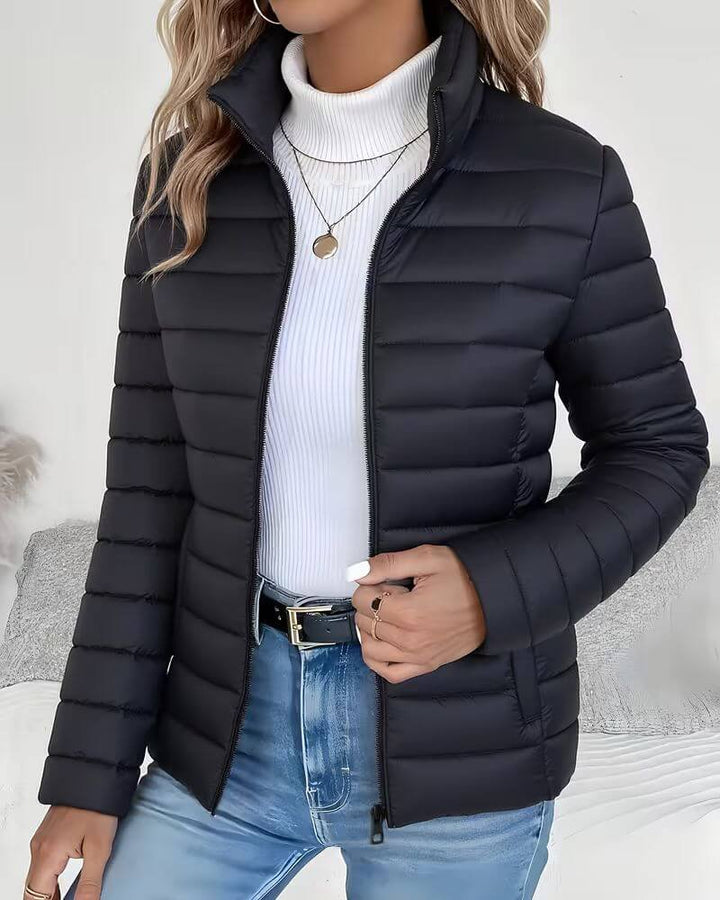 Lightweight women's puffer jacket with a stand collar, featuring a quilted design and hip-length cut, perfect for winter wear. 1